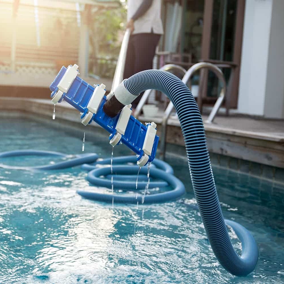 Akron pool cleaner vacuuming a backyard pool with bright blue water.